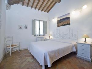 a white bedroom with a white bed and a chair at Apartment Pienza by Interhome in Vergelle
