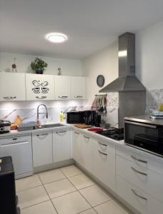 a kitchen with white cabinets and a stove top oven at Une petite chambre jardin in Dijon