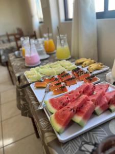 a table with several plates of watermelons and other foods at ACOMODARE HOTEL- SOB NOVA Direção in Tubarão