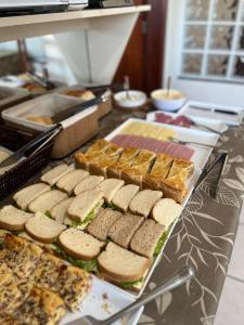a buffet with sandwiches and other food on a table at ACOMODARE HOTEL- SOB NOVA Direção in Tubarão