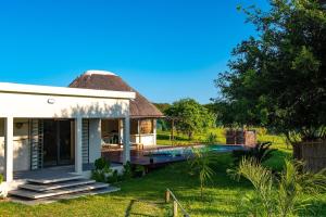 a house with a thatched roof and a swimming pool at Ka Nicita - Beach house with pool in Praia de Macaneta