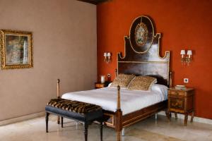 a bedroom with a large bed and orange walls at Hotel Boutique Palacio Arudecas in Cañada de Calatrava