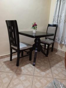 a black table with two chairs and a vase with flowers at Voi town CBD homes in Voi