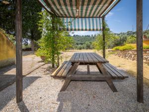 a wooden picnic table under a pergola at Apartment Erica by Interhome in Venturina Terme