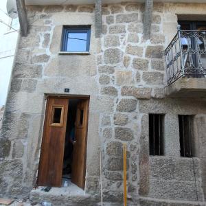 a stone building with a wooden door and a balcony at Casa Fornos de Amor in Fornos de Algodres