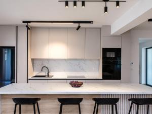 a kitchen with white cabinets and a counter with chairs at Villa Antica by Interhome in Lopar
