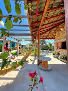 a patio with a hammock and tables and flowers at Loft Verde - Pousada Vila Dondom in Luis Correia