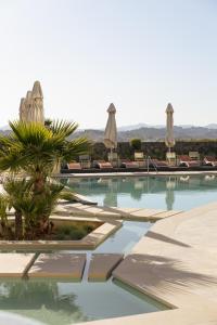 a swimming pool with chairs and umbrellas at Divani Corfu Palace in Corfu