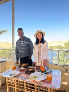 a man and woman standing next to a table with food at Rayan Nubian Guest House in Aswan