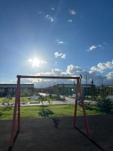 a swing set in a park with the sun in the sky at Ademi cottage in Koshkolʼ