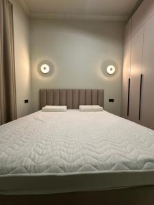 a large bed in a bedroom with two lights on the wall at Ademi cottage in Koshkolʼ