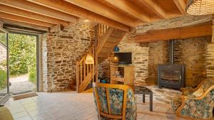 a living room with a fireplace and a stone wall at Gite champêtre in Tréal