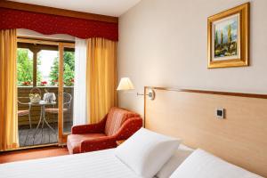 a hotel room with a bed and a chair at Terme Banovci - Hotel Zeleni Gaj in Banovci
