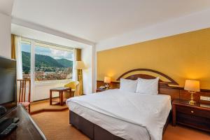 a hotel room with a bed and a large window at Hotel Aro Palace in Braşov