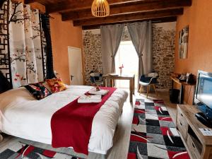 a bedroom with a large bed and a television at La Synchronicité - Chambres d'Hôtes in Vaudrimesnil