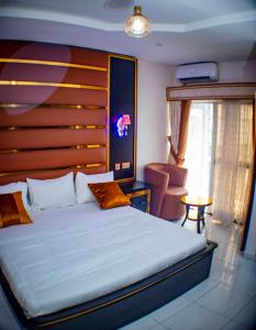 a bedroom with a large bed and a chair at Pretelia Hotel in Warri +22 photos