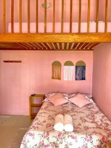 a bedroom with a bed with two slippers on it at Loft Rosa - Pousada Vila Dondom in Luis Correia +14 photos