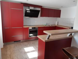 a red kitchen with red cabinets and a sink at Le Pélerin in Saignelégier