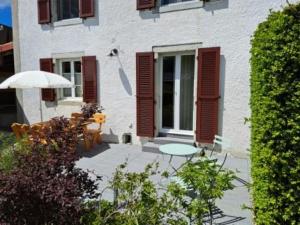 a patio with a table and an umbrella in front of a building at Le Pélerin in Saignelégier