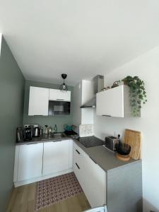 a kitchen with white cabinets and a sink at Une jolie vue - Appt 2 pièces - Vue mer Balcon sud - 150m de la plage in Wimereux +7 photos