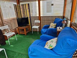 a screened in porch with blue chairs and a tv at En Resort Fincas Las Dunas dos Chalets con jacuzzis en primera linea de playa , uno de 4 dormitorios y otro de 2 dormitorios, Llama al Seiscientos veintisiete Cuatrocientos diecisiete Trescientos noventa y ocho in Rota