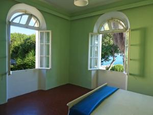 a bedroom with two windows and a bed with blue sheets at Romantic rooms with stunning sea view in Rhodes Town