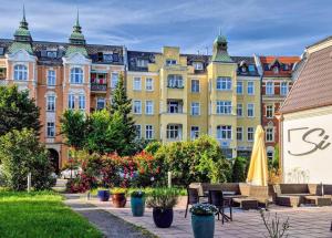 a row of buildings in a park with benches and flowers at Grand Park Hotel in Szczecin