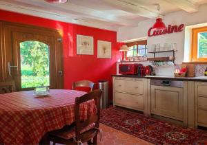 a kitchen with a table and a red wall at La Grange de Jeanne in Moosch +4 photos
