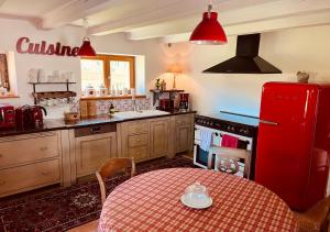 a kitchen with a table and a red refrigerator at La Grange de Jeanne in Moosch