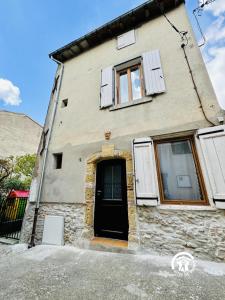 a stone house with a black door and windows at Oustal marcellin in Fanjeaux