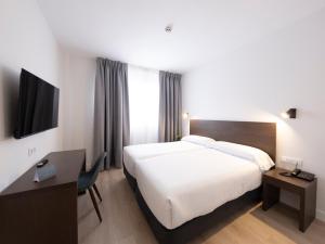 una habitación de hotel con una cama grande y un televisor en Hotel Cisneros, en Alcalá de Henares