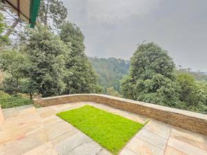 an outdoor patio with green grass and a wall at Silent Stone Homestay in Almora +2 photos