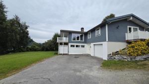 a large house with a driveway in front of it at Fjordside Apartment in Åndalsnes