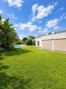 a yard with a white building and a pool at Three on Firmount in Somerset West