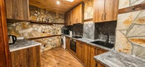 a kitchen with wooden cabinets and a stone wall at Rhodopski Apartment in Chepelare