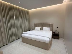 a bedroom with a large bed with white sheets and pillows at شقة مودرن غرفة وصالة in Buraydah