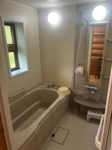 a bathroom with a large tub and a toilet at Kamishiro Mountain Lodge in Hakuba
