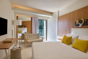 a hotel room with a bed and a living room at Atlantica Nissaki Beach - Adults Only in Gimari +134 photos