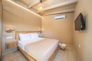a bedroom with a bed and a flat screen tv at Sea salt house in Zambelláta