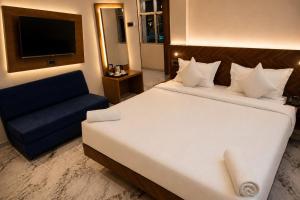 a bedroom with a large white bed and a blue couch at The Blue Inn Hotel in Hyderabad