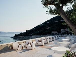 a row of white chairs and tables on a deck at Atlantica Nissaki Beach - Adults Only in Gimari
