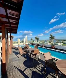 a rooftop deck with tables and chairs and a swimming pool at West Flat - BarretoStays 02 in Mossoró