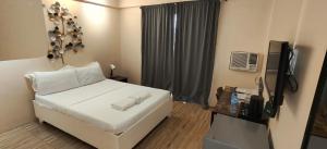 a bedroom with a white bed and a television at Hotel Casa Ilustre in Balayan +1 photo