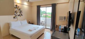 a bedroom with a bed and a tv and a window at Hotel Casa Ilustre in Balayan