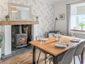 a dining room with a table and a fireplace at Torr Cottage in Dalrymple