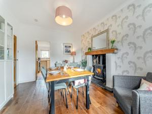 a dining room with a table and chairs and a fireplace at Torr Cottage in Dalrymple