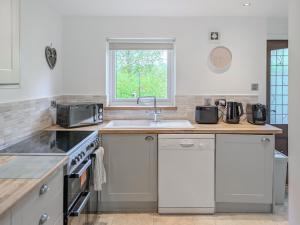 a kitchen with white appliances and a sink at Torr Cottage in Dalrymple