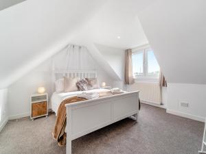 a white bedroom with a bed and a desk at Torr Cottage in Dalrymple