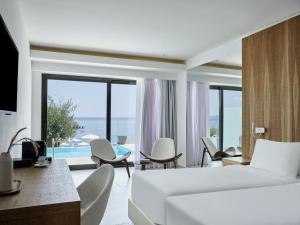 a bedroom with a bed and chairs and a view of the ocean at Atlantica Nissaki Beach - Adults Only in Gimari