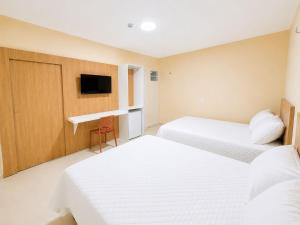 a hotel room with two beds and a tv at Pousada Milagres in Canindé